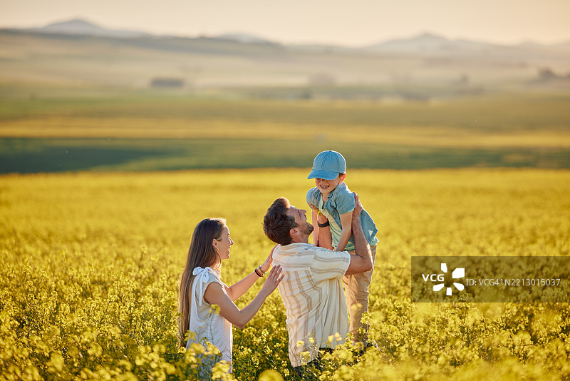微笑的父母与孩子在田野中玩耍，享受夏季假期、度假旅行和乡村亲子时光。快乐的家庭和孩子在花海中享受自然旅行、探索和周末休闲。图片素材
