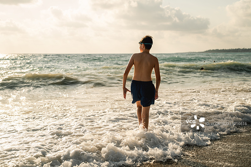 放松的少年在日落时分奔向暴风雨中的大海图片素材