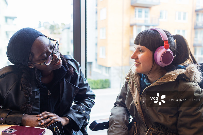神经多样性青少女与个人护理助理在咖啡馆窗边的快乐时光图片素材