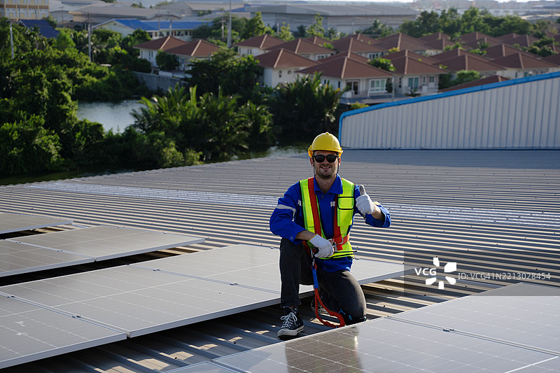 蓝领工人在工厂的太阳能面板屋顶上工作。图片素材