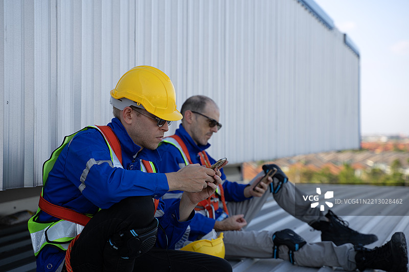 蓝领工人在工厂的太阳能面板屋顶上工作。图片素材