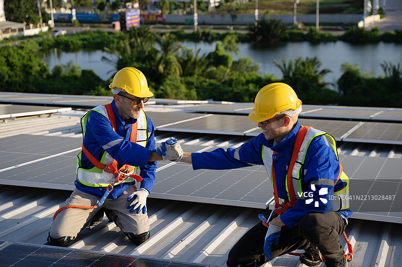 蓝领工人在工厂的太阳能面板屋顶上工作。图片素材