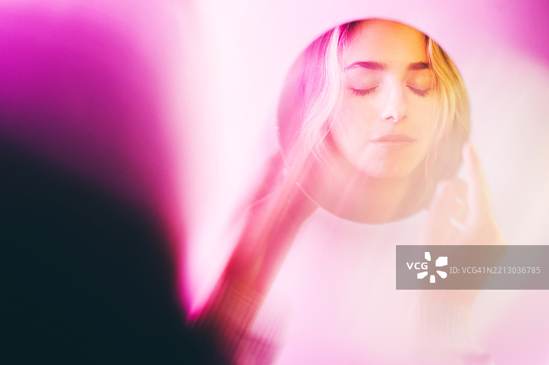 一个青少年女孩在镜子中倒影。霓虹色。图片素材