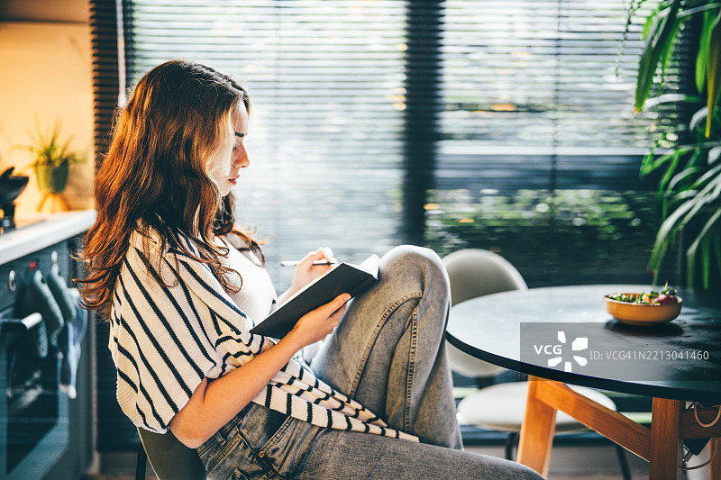 在家中认真写笔记的女性。图片素材