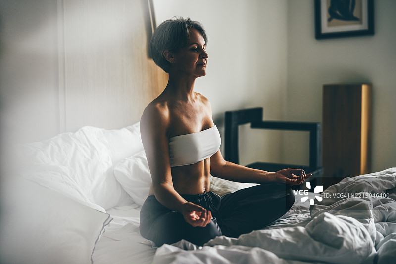 女人在家床上冥想。图片素材
