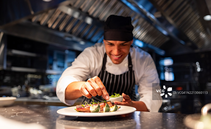 厨师在商业厨房中装饰盘子同时烹饪图片素材