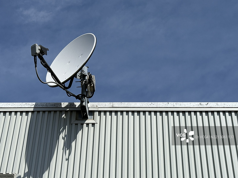 日本蓝天上安装在金属屋顶结构上的卫星天线图片素材