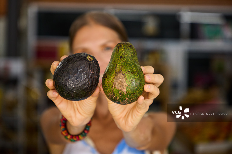 在商店环境中展示两种不同类型鳄梨的人图片素材