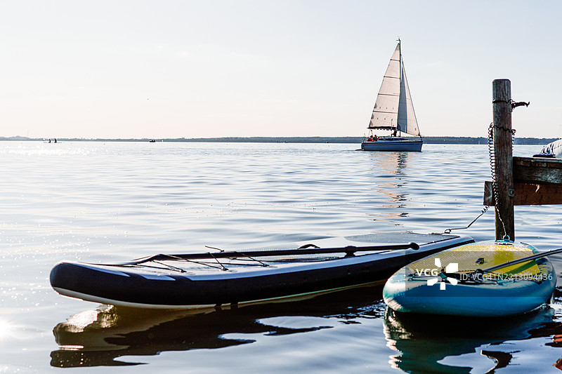 宁静的湖面场景，日出时的帆船和划水板图片素材