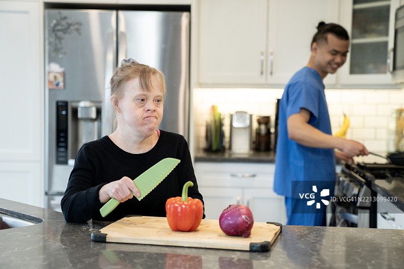 微笑的女性在厨房中愉快地烹饪，享受着帮助的乐趣图片素材