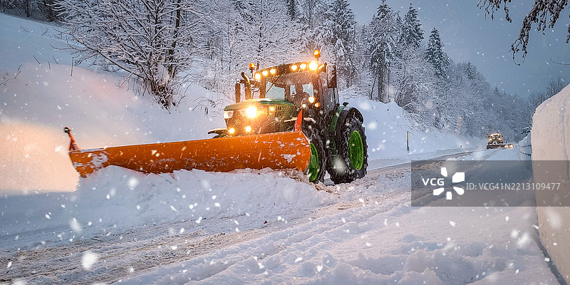 雪铲卡车在大雪中清理道路图片素材