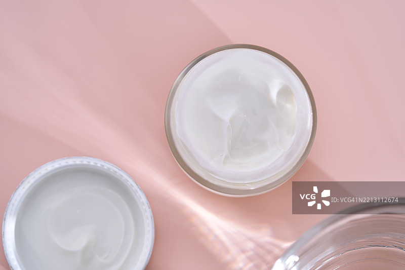 一个盛有奶油的打开罐子，背景为粉色。图片素材