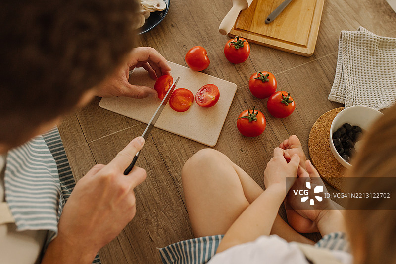 家庭在温馨的厨房环境中准备新鲜的番茄和食材图片素材