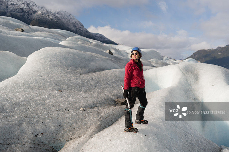 微笑的女性冰川学家正在用冰镐探索冰川图片素材