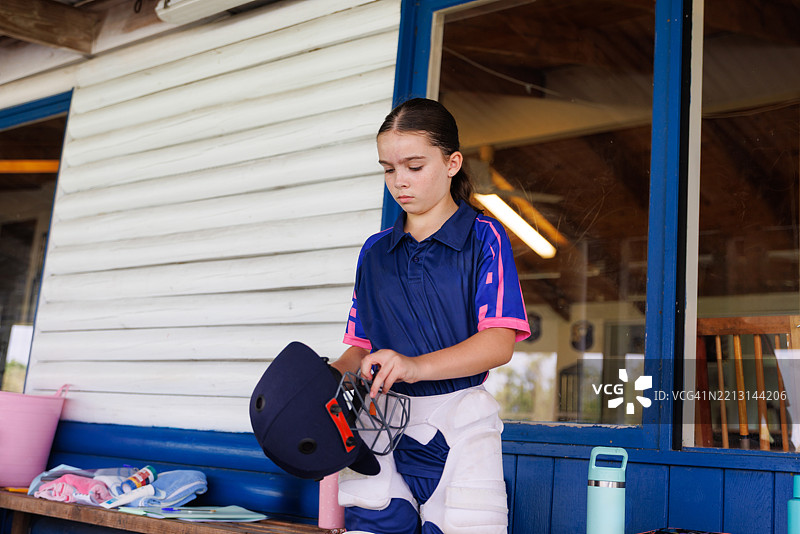 年轻女性板球运动员正在戴上头盔图片素材