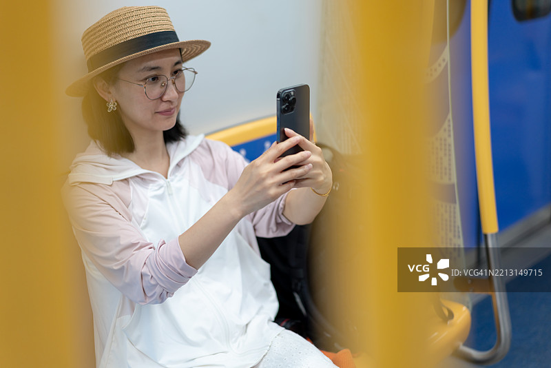 一位亚洲女性在地铁中使用手机进行面部识别。图片素材