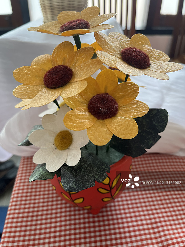 手工纸花束放在格子桌布上的装饰花瓶中图片素材