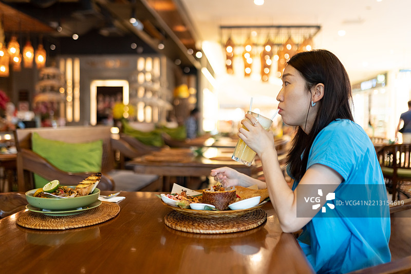 一位亚洲女性在餐厅品尝酸汁图片素材
