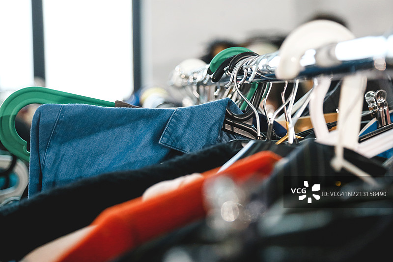 车库销售和二手概念。街头跳蚤市场上的衣架上挂着五颜六色的棉质和牛仔衣物。图片素材