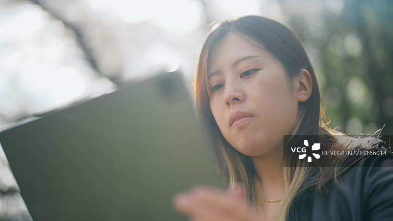 女性数字艺术家在公园的草地上放松，使用平板电脑绘画。图片素材