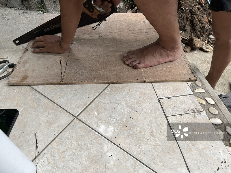 男子在户外用手锯切割胶合板 - DIY木工活动图片素材