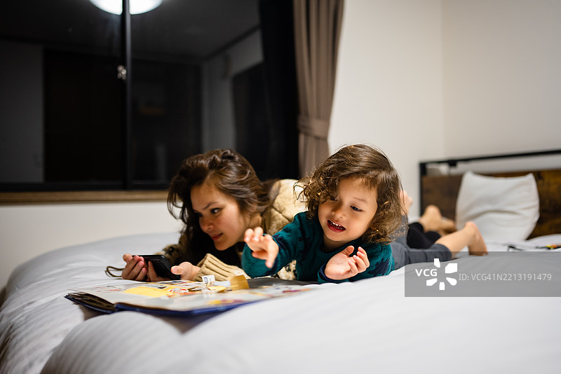 母亲在温馨的卧室里给儿子讲睡前故事图片素材