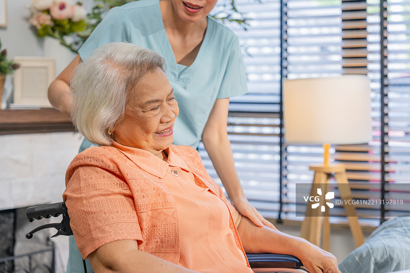 亚洲护士物理治疗师医生正在接触一位亚洲老年女性患者，亚洲护理人员在家中护理中心帮助老年女性进行物理治疗。图片素材