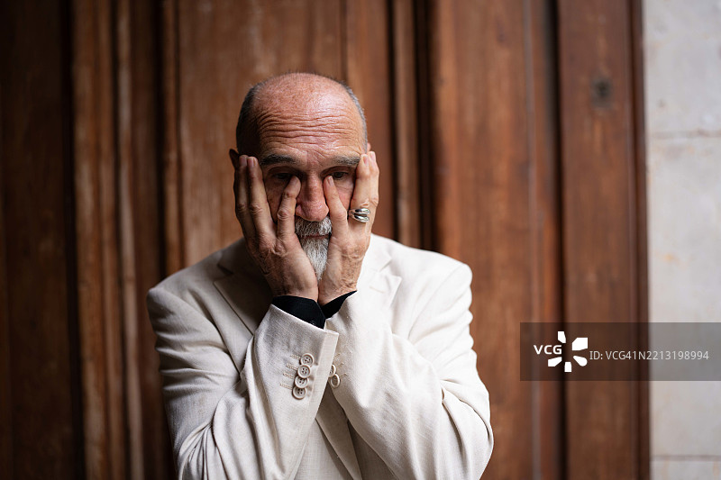 秃顶的老年男子用手指触摸自己的脸和眼睛。忧伤的成年人。抑郁，失眠的概念。图片素材