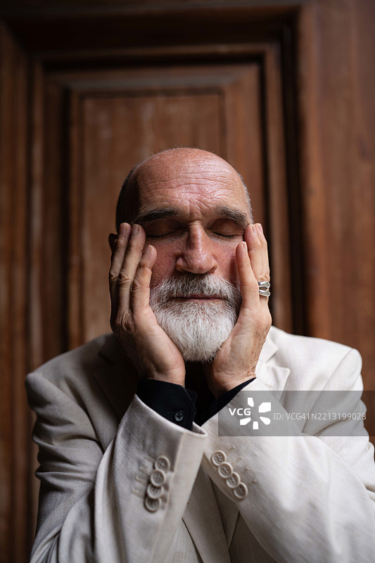 秃顶的老年男子用手指触摸自己的脸和眼睛。忧伤的成年人。抑郁，失眠的概念。图片素材