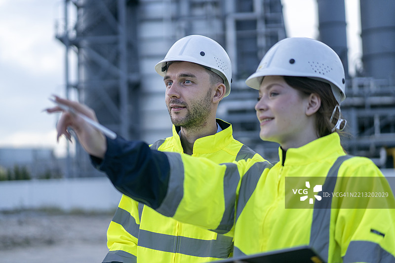 两名工程师在炼油厂熬夜使用笔记本电脑工作。图片素材