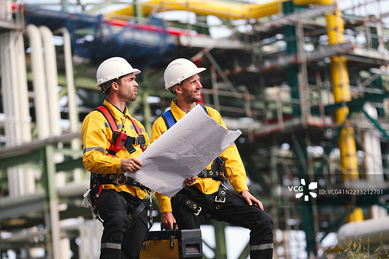 两名穿着安全服和安全帽的工程师在石油管道和管架工业区的背影图片素材
