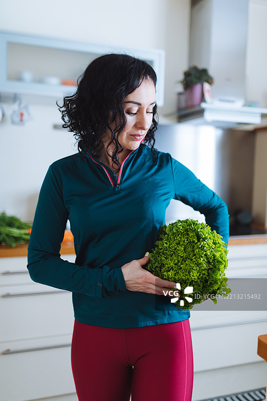 女性在明亮现代的厨房中手持新鲜生菜图片素材