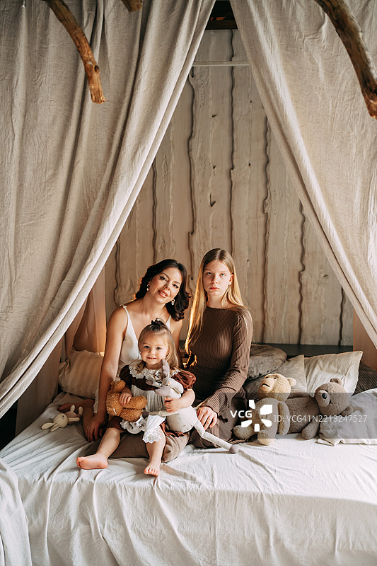 母亲和女儿们在床上与泰迪熊合影图片素材