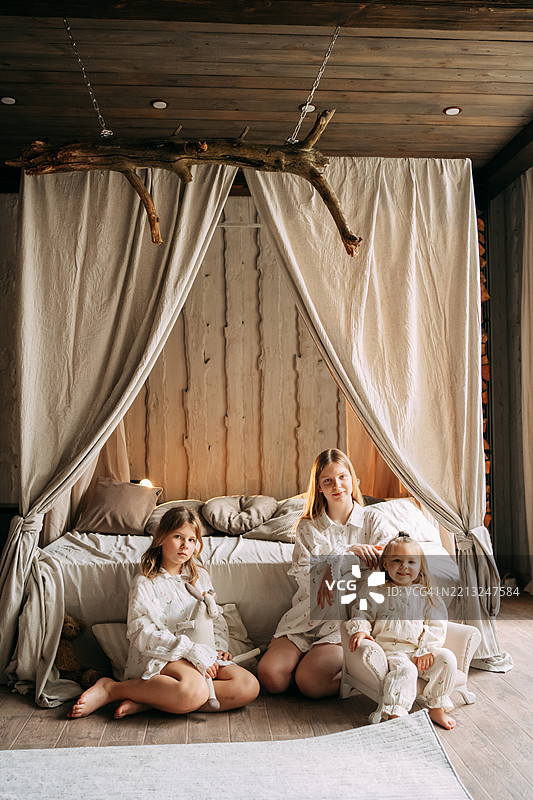 母亲和女儿们在温馨的乡村卧室里摆姿势图片素材