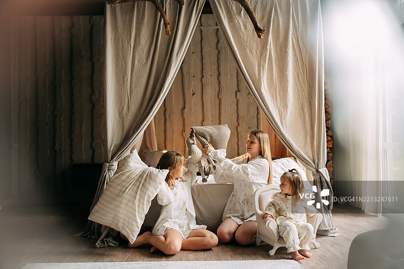 母亲和女儿们在卧室里打枕头大战图片素材