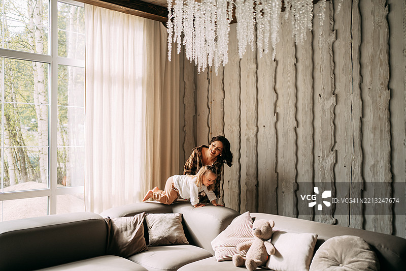 母女在现代客厅的沙发上玩耍图片素材