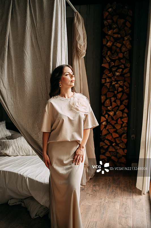 优雅的女性在舒适的卧室内穿着时尚的米色服装摆姿势图片素材