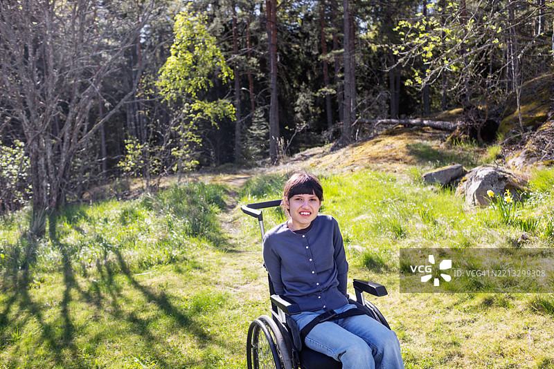 坐在轮椅上的神经多样性青少年女孩在宁静的林地中享受时光图片素材