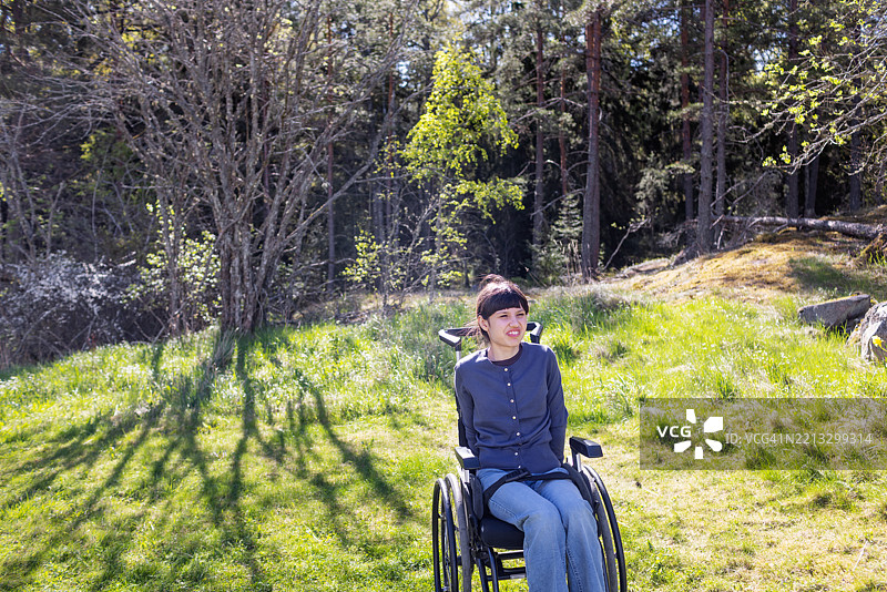 坐在轮椅上的神经多样性青少年女孩在宁静的林地中享受时光图片素材