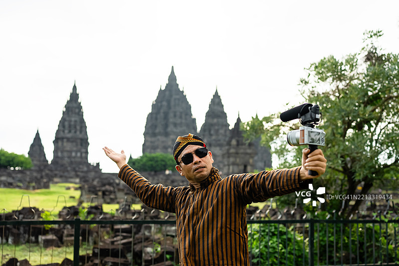 迷人的成熟男性在录制视频博客，一位游客在普兰巴南寺记录他的旅行经历，捕捉美好回忆。图片素材