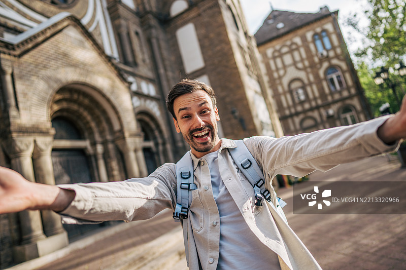 快乐的游客在欧洲城市的教堂前自拍图片素材