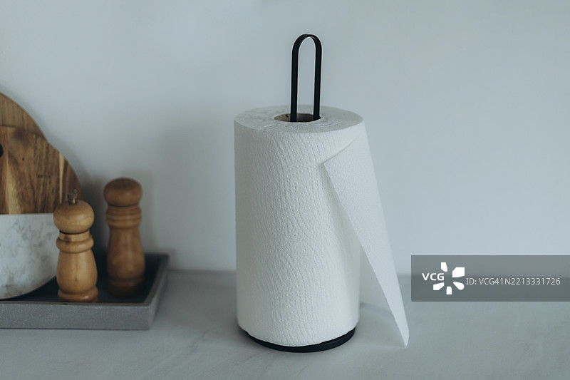 纸巾架旁边放着一个托盘，上面有木质切菜板、盐和胡椒研磨器。图片素材