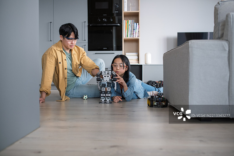 父亲在教女儿关于STEM、机器人技术，并讨论科技。图片素材