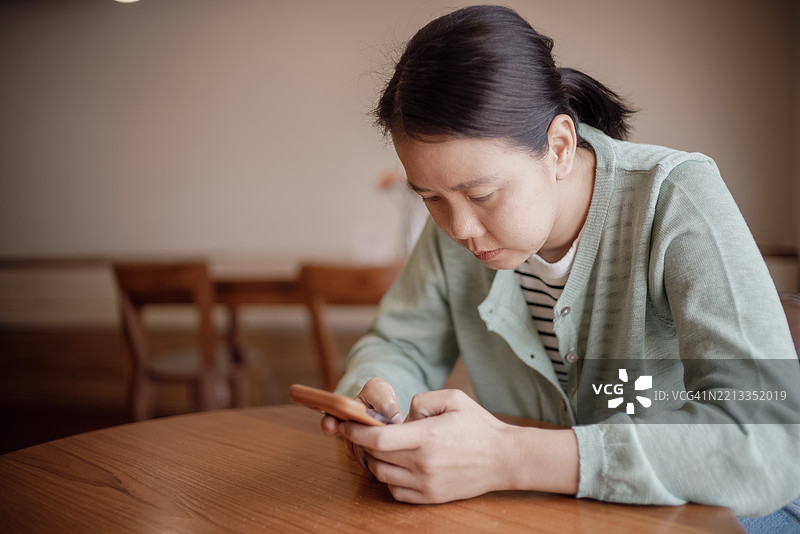 年轻的亚洲女性在家中接到一个未知来电并拒绝接听，手机诈骗者概念。图片素材