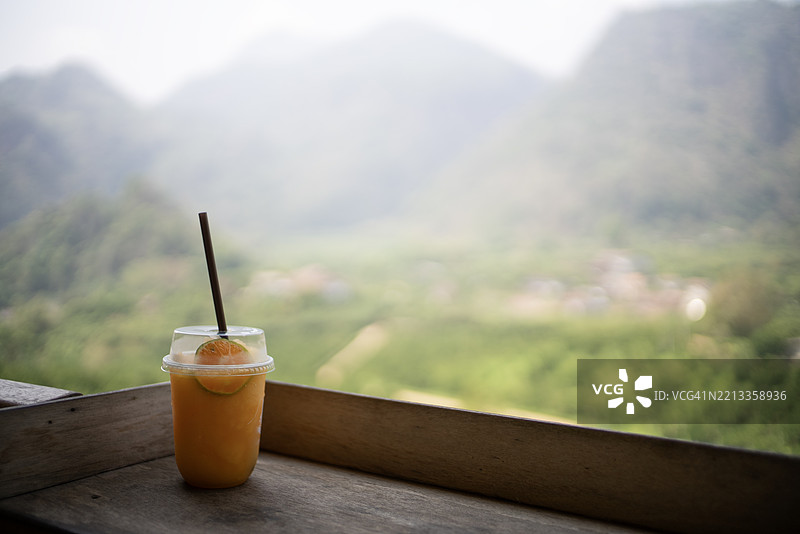 聚焦于橙汁杯，背景是山脉图片素材