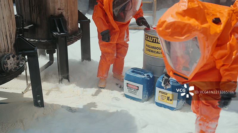 两名穿着反射防护服的专家在危险区域收集有害物质。图片素材