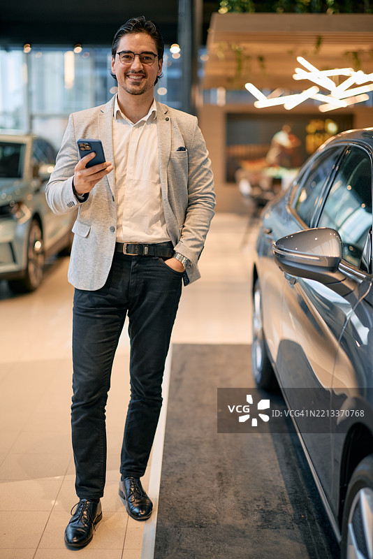 商人在汽车展厅里使用智能手机选择新车图片素材