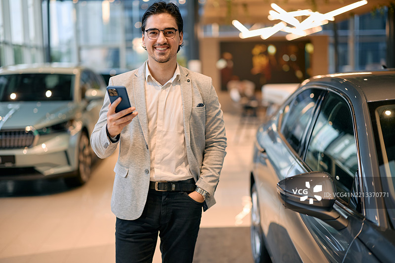 商人在汽车展厅使用智能手机选择新车图片素材