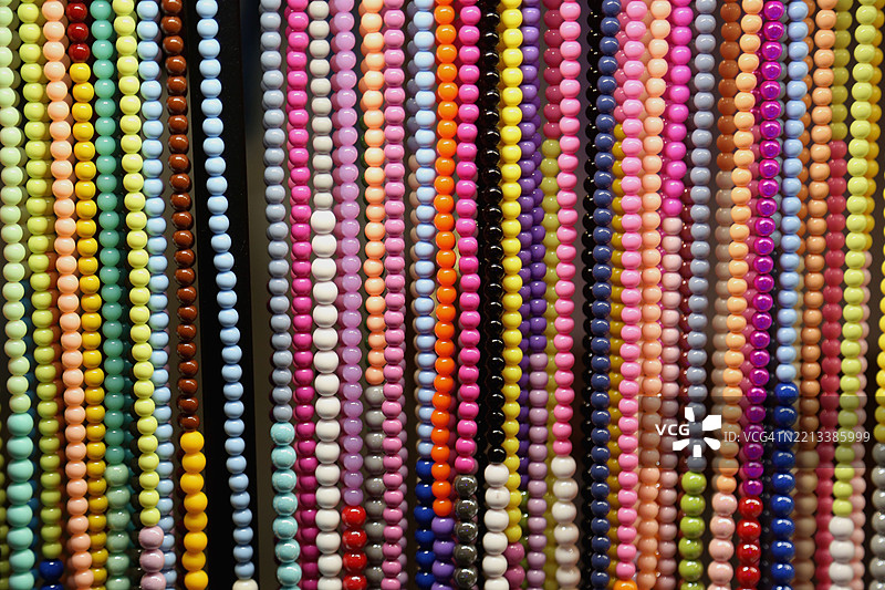 全景抽象珠宝背景。街头跳蚤市场上成排的霓虹色项链堆积在一起。图片素材