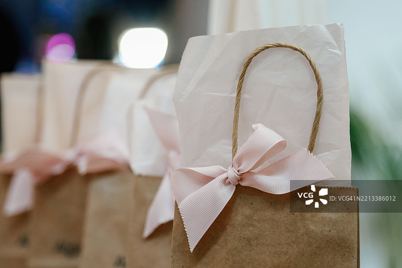 一排精美的棕色纸购物袋，配有优雅的粉色丝带，专为她而设计图片素材